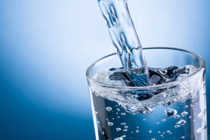 Pouring water into glass on blue background